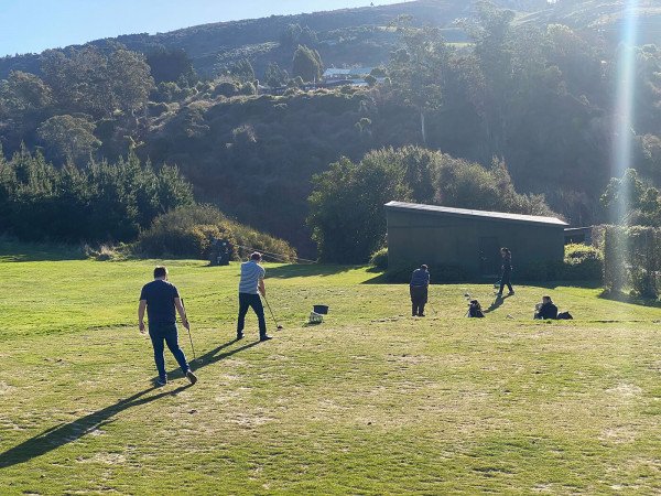 Team members lined up at the driving range bays surrounded by native bush