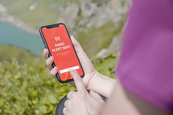 Solo hiker on a remote trail relying on a personal safety app for check-ins
